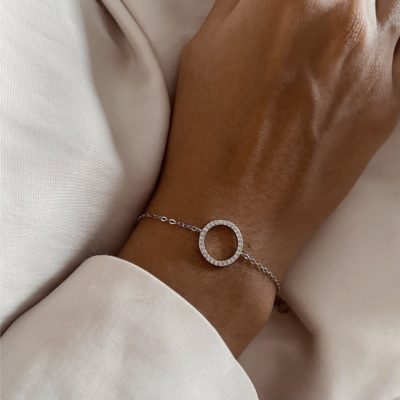 צמיד מעגל החיים כסף 925 עדין עם תליון עגול משובץ זרקונים על פרק יד נשי, רקע בד בהיר