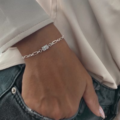 צמיד זנזיבר מלבן כסף אמיתי 925 עם חוליית אובאל ועיטור זירקון מרובע, על פרק יד נשי עם חולצה בצבע בהיר ומכנסי ג’ינס.