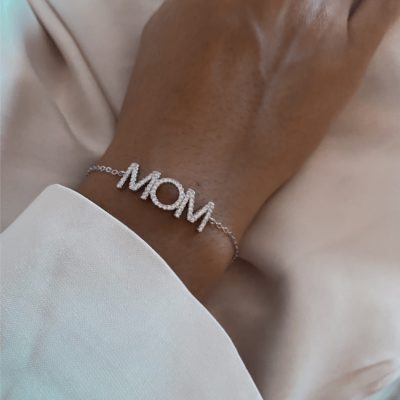 צמיד MOM כסף אמיתי 925 עדין עם תליון MOM משובץ זרקונים, על יד של דוגמנית עם חולצה לבנה.