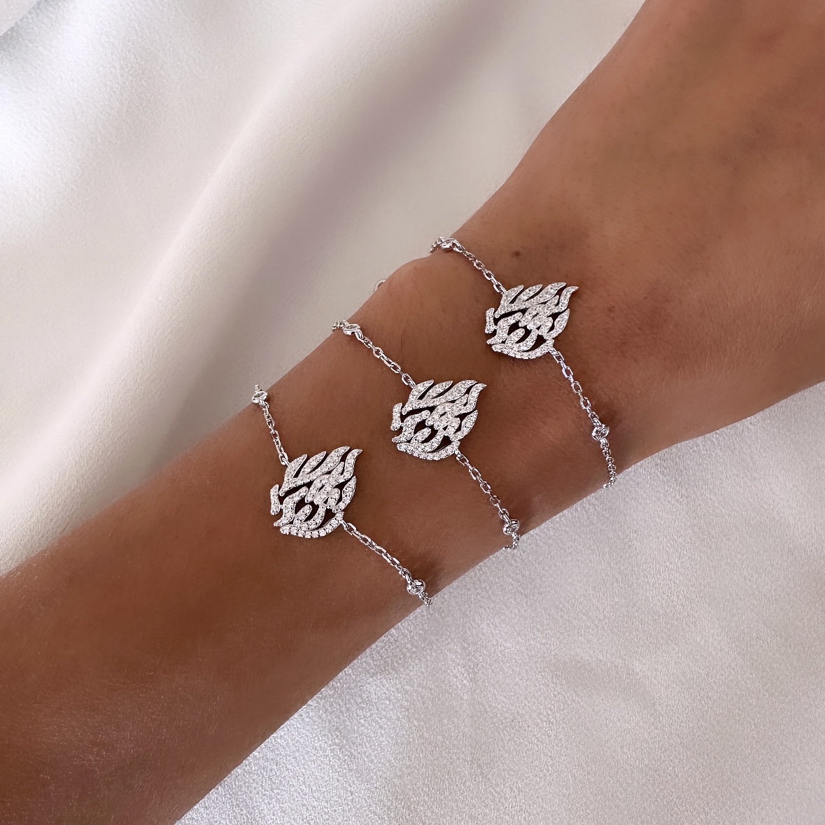 שלושה צמידי כסף 925 בעיצוב האש שלי משובצת זרקונים על יד של דוגמנית