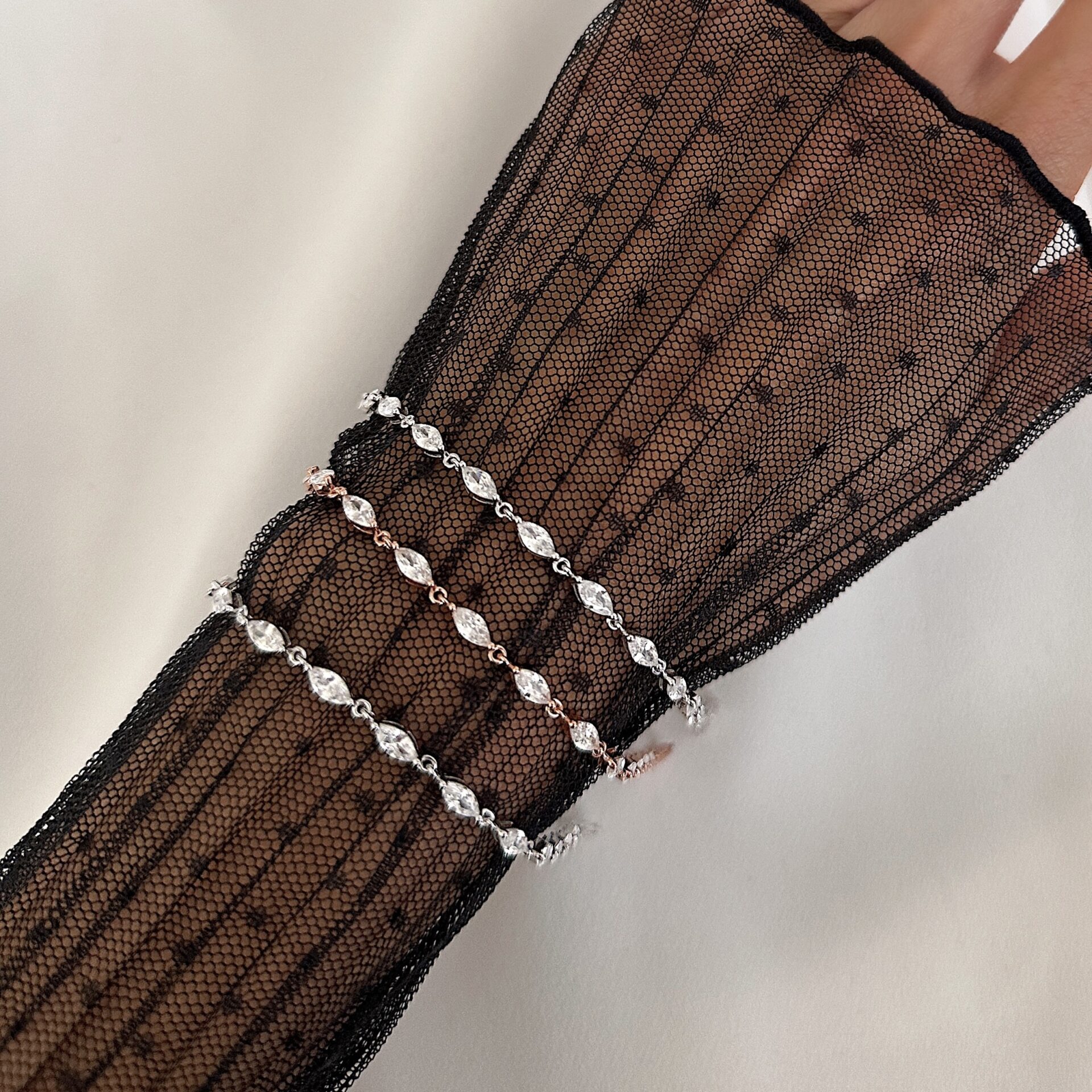 צמיד מרקיזה כסף 925 ורוז גולד משובצים זרקונים בעיצוב אליפסה על יד של דוגמנית עם שרוול תחרה שחורה