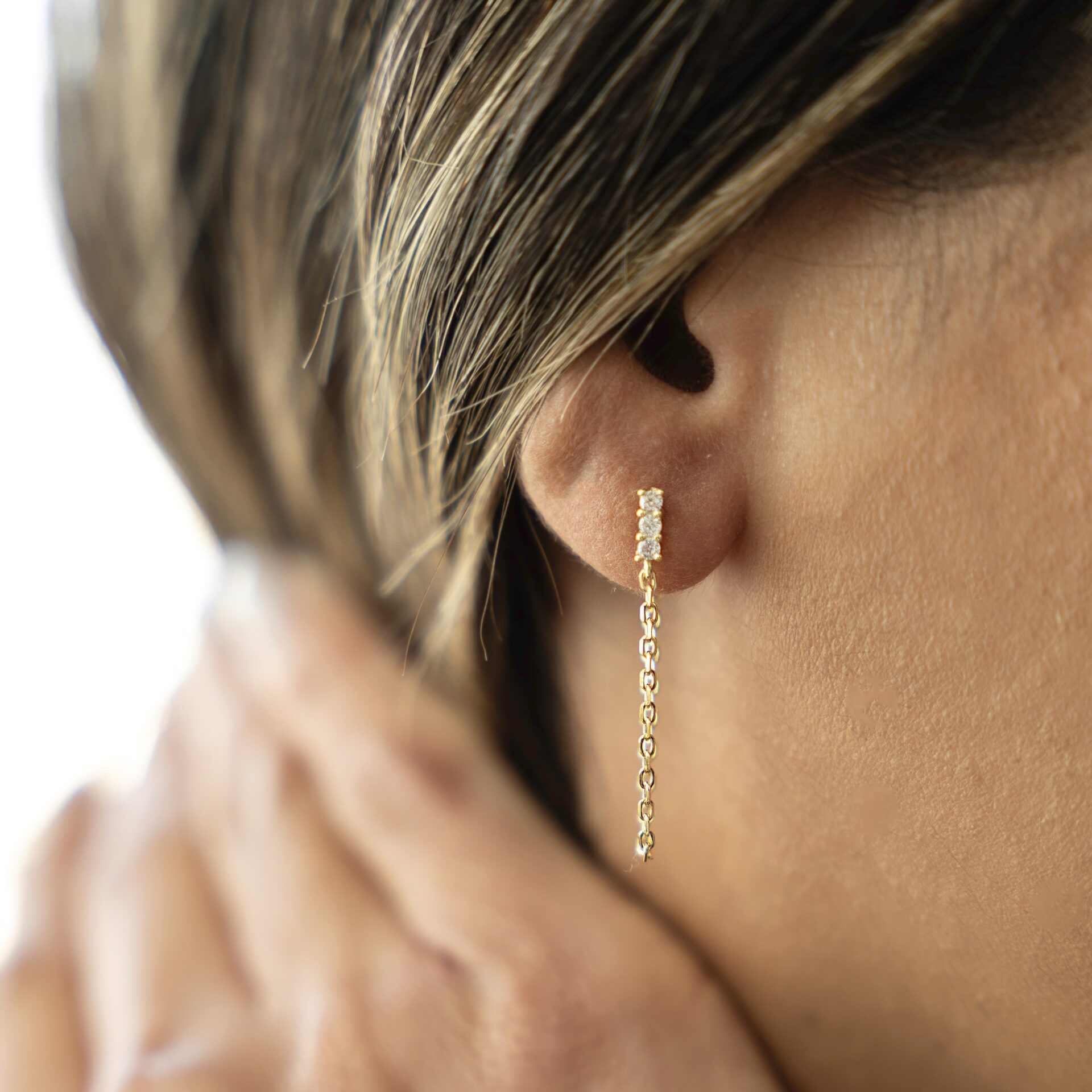 עגיל שרשרת זהב משובץ זרקונים על אוזן דוגמנית