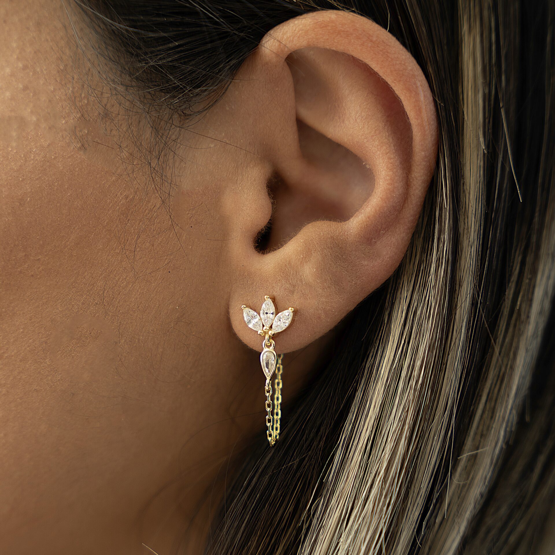 עגיל זהב בעיצוב עלה משובץ זרקונים עם שרשרת עדינה על אוזן דוגמנית