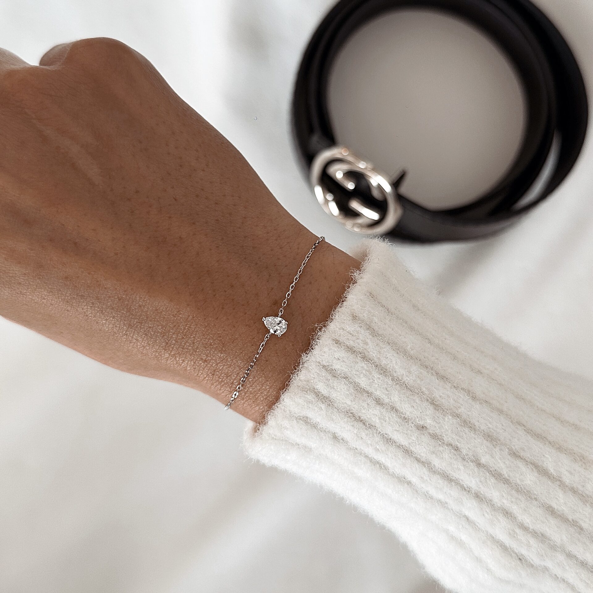 צמיד טיפה עדין כסף אמיתי 925 משובץ זירקון נוצץ על פרק יד של אישה עם סוודר לבן