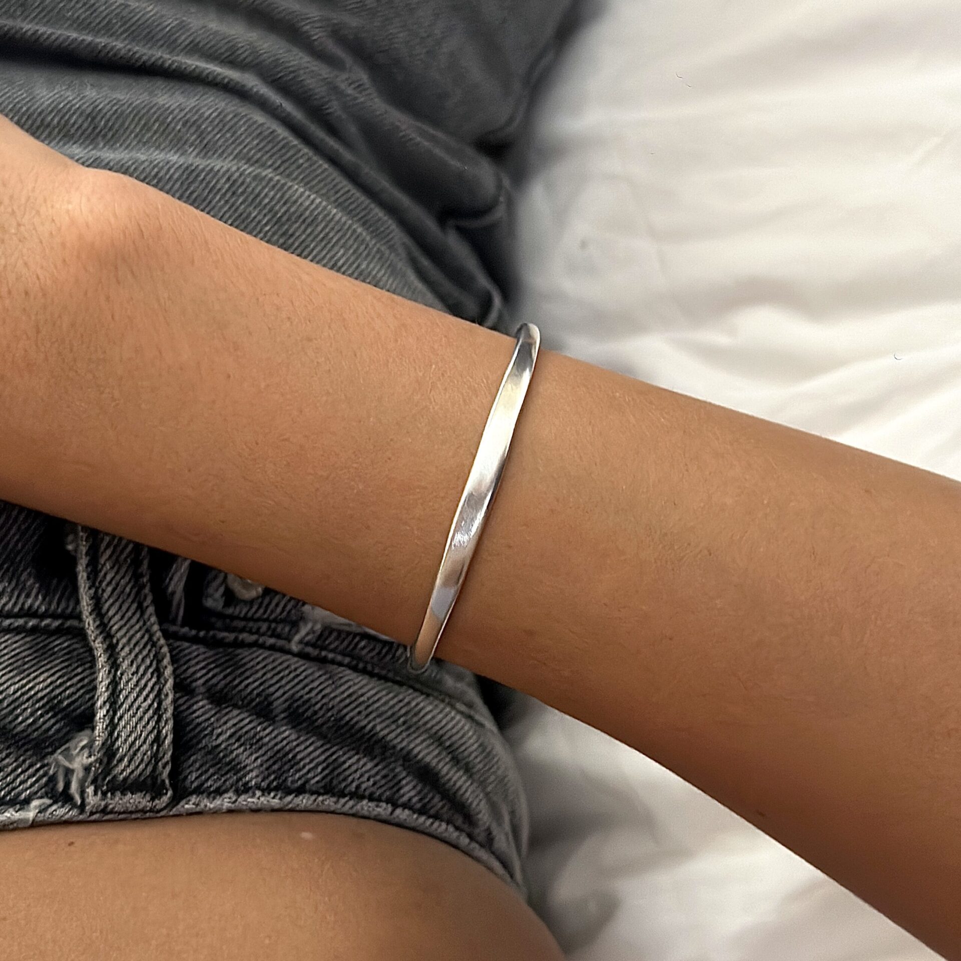 צמיד קשיח כסף אמיתי 925 חלק על יד של אישה עם מכנסי ג'ינס