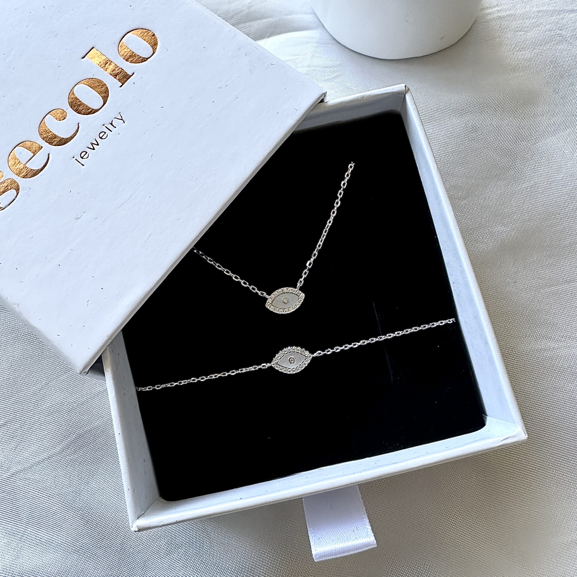 סט תכשיטים צדף שרשרת וצמיד מכסף אמיתי 925 על מצע קטיפה שחור וקופסא של סקולו עם לוגו